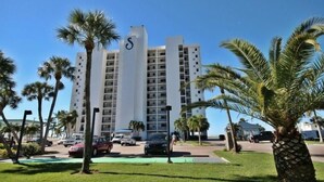 Un hôtel à plusieurs étages, reconnaissable à son logo en forme de « S » bien visible, entouré de palmiers et doté d’un parking.