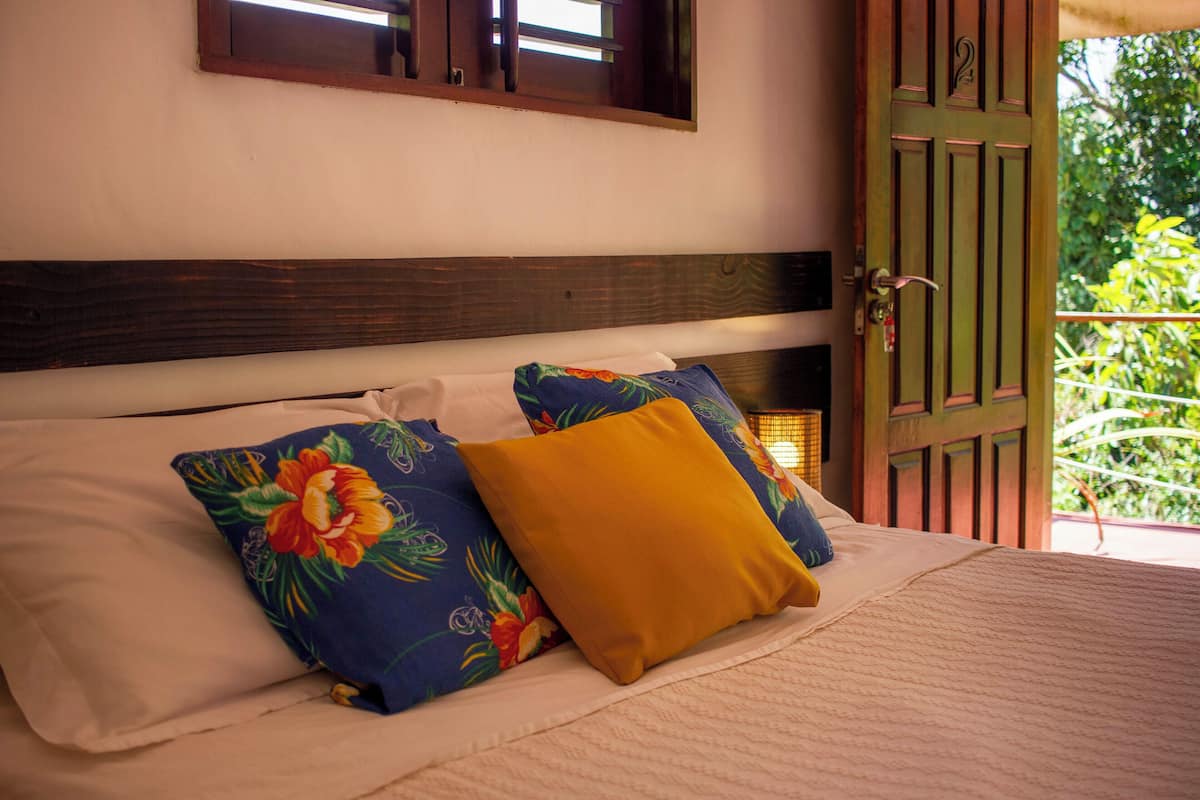 Un lit avec des coussins à motifs floraux et une tête de lit en bois.