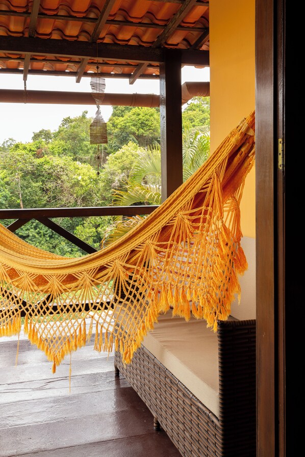 Una hamaca colgada en un balcón con vistas a un follaje exuberante.