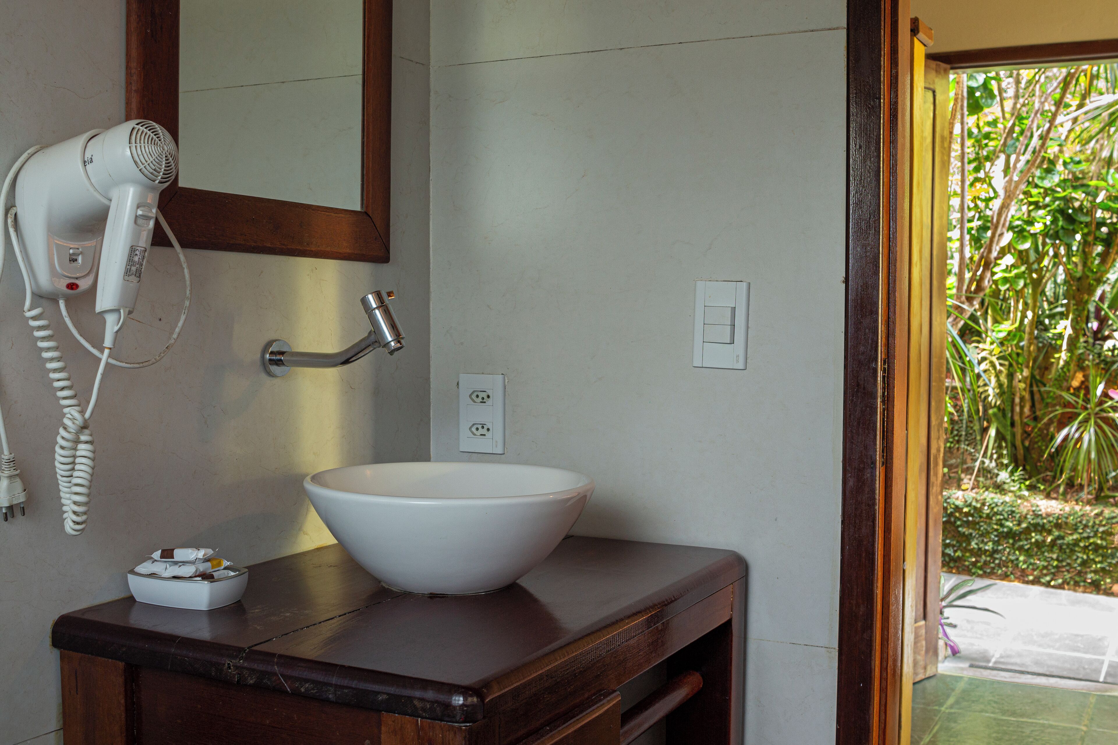 A bathroom with a white sink, a hairdryer, and a mirror.