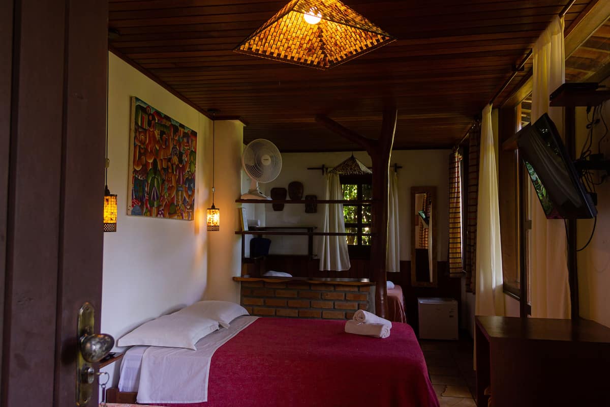 Une chambre d’hôtel avec un lit, un ventilateur, une télévision et un tableau au mur.