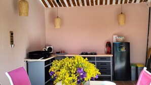 A dining area with a table set for four, a kitchen in the background, and a ceiling with wooden beams. - PRETTY PROVENCAL VILLA IN THE HEART OF THE LUBÉRON PARK 7 MIN FROM GORDES (Saint-Saturnin-lès-Apt)