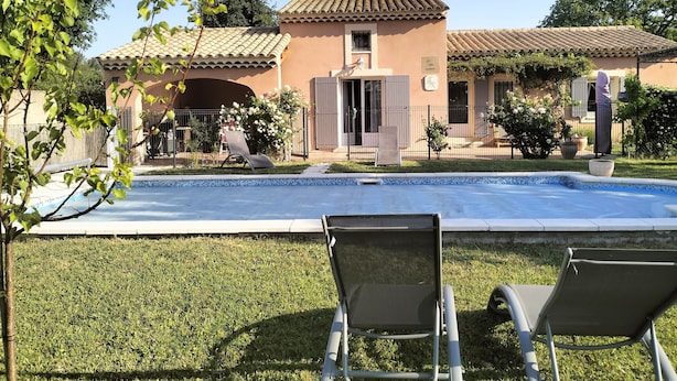A swimming pool with lounge chairs, a building with a tiled roof, and a fenced garden area. - PRETTY PROVENCAL VILLA IN THE HEART OF THE LUBÉRON PARK 7 MIN FROM GORDES (Saint-Saturnin-lès-Apt)