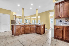 A spacious kitchen with a large island, wooden cabinets, and a tiled floor.
