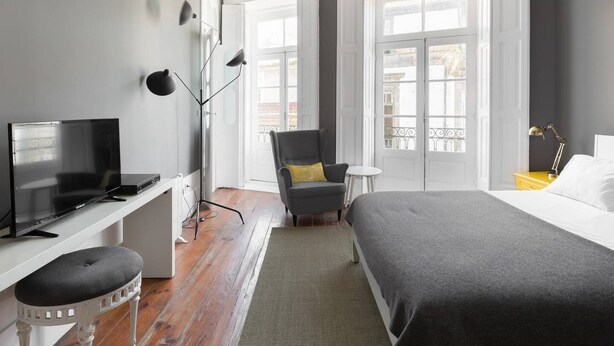 Ein modernes Hotelzimmer mit Bett, Schreibtisch mit Fernseher, Stuhl und Balkonblick.