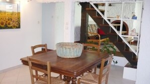 Un comedor con una mesa y sillas de madera, una cesta tejida y una escalera que sube a un nivel superior.