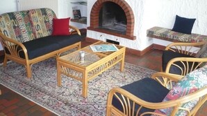 Un salón con muebles de mimbre, una alfombra estampada y una chimenea.