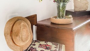 A wooden table with a vase of flowers, a straw hat, and decorative pillows. - Naples Center Apartment (Napoli)