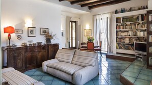 A cozy living room with a sofa, a bookshelf, and a dining area. - Naples Center Apartment (Napoli)