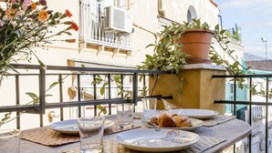 A balcony with a table set for breakfast, including croissants and water glasses. - Naples Center Apartment (Napoli)