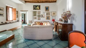 A spacious living room with a large sofa, a wooden cabinet, and a tiled floor. - Naples Center Apartment (Napoli)