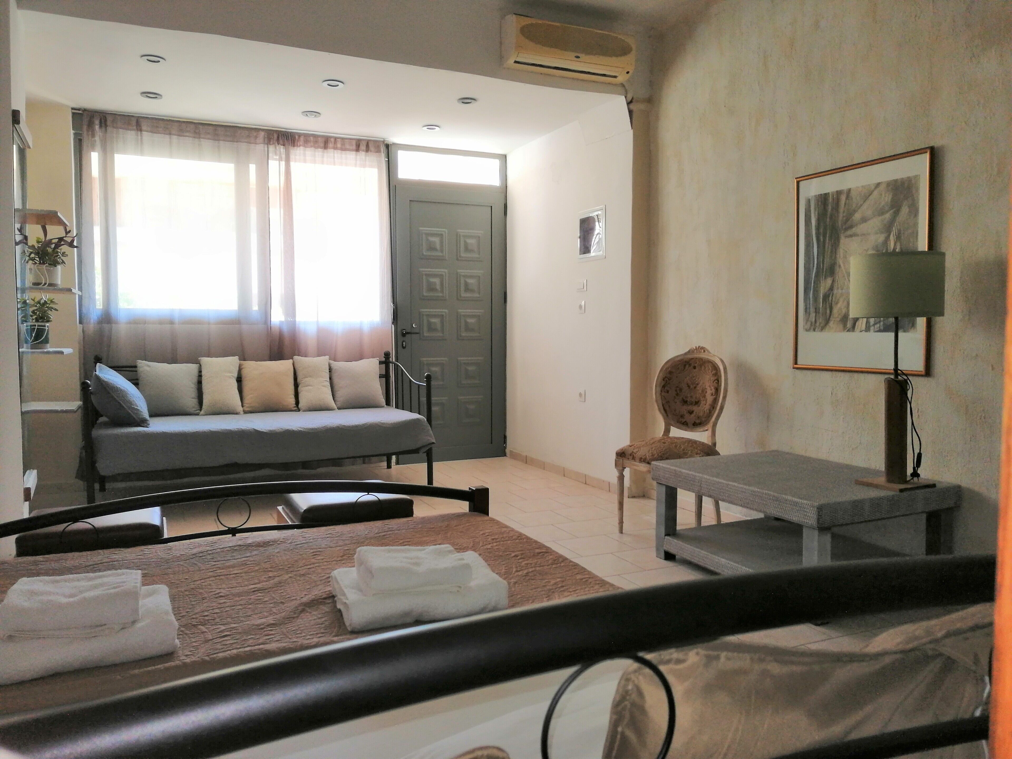 Habitación de hotel con cama, sofá, sillón, mesa y un cuadro en la pared.