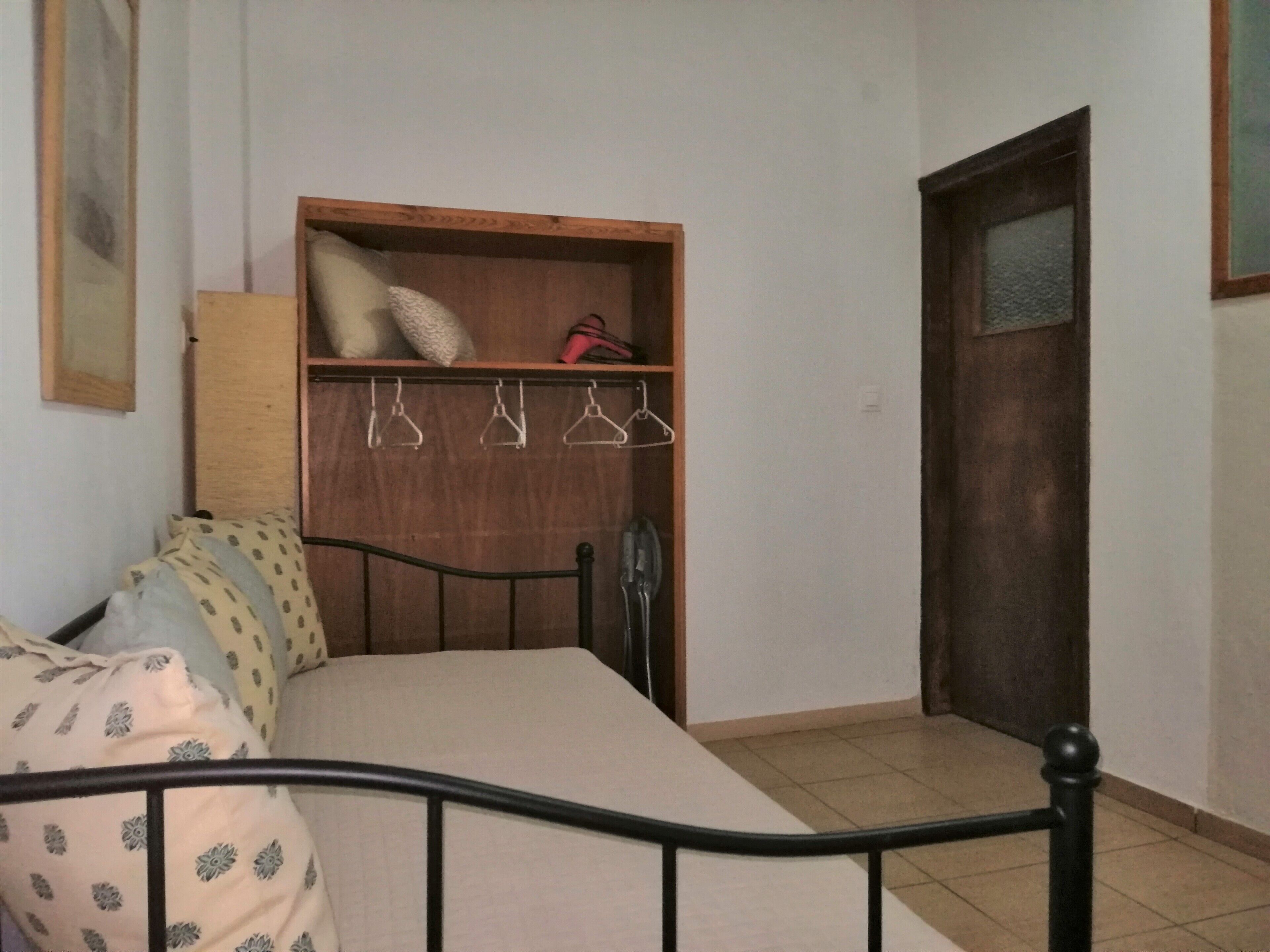 A bedroom with a bed, wooden wardrobe, and a door.