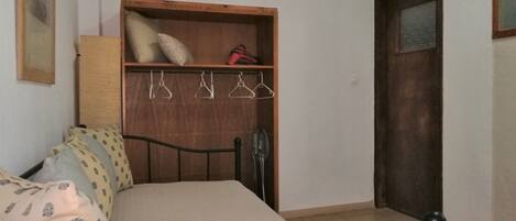 A bedroom with a bed, wooden wardrobe, and a door.