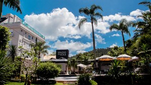 A hotel named "Spazio del Sole" with a clear blue sky, palm trees, and a well-maintained garden. - Spazio del Sole Jurere (Florianópolis)