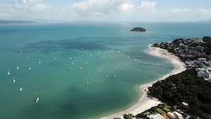 An aerial view of a coastal area with a beach, boats, and a small island. - Spazio del Sole Jurere (Florianópolis)