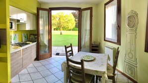 Eine Küche mit Essbereich, einem Fernseher und Blick auf einen Garten.