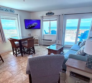 A living room with a TV, wicker furniture, a glass coffee table, and a sofa.