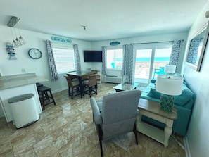 Un soggiorno con zona pranzo, una TV a parete e vista mare.