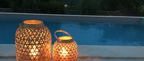 Dos faroles junto a una piscina con montañas al fondo.