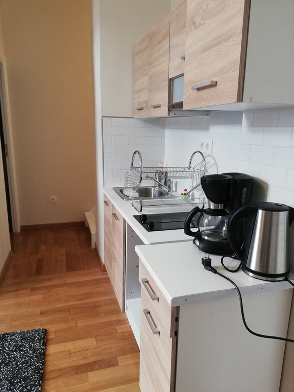 Compact kitchen with light cabinetry, white subway tiles, and a stainless steel sink.