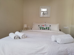 Relax in a serene space with a large bed, nightstand, and lamp, perfect for a restful stay.