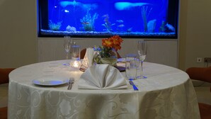 A round table set for dining with a fish tank in the background. - Sonia Hotel (Accra)