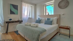 A bedroom with a bed, bedside table, and a window.