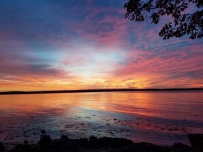 A sunset over a calm body of water with a rocky shoreline. - Oceanfront home on the Schoodic Peninsula (Gouldsboro)