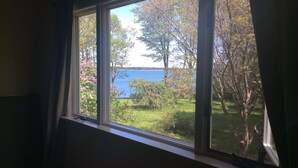 Ett rum med ett stort fönster med utsikt över en trädgård och en vattenyta.