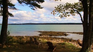 En vacker utsikt över sjön med två Adirondack-stolar och en Adirondack-eldstad.