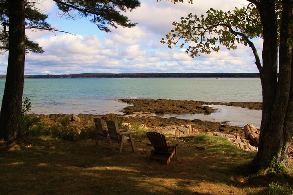 A lakeside view with two Adirondack chairs and a Adirondack fire pit. - Oceanfront home on the Schoodic Peninsula (Gouldsboro)