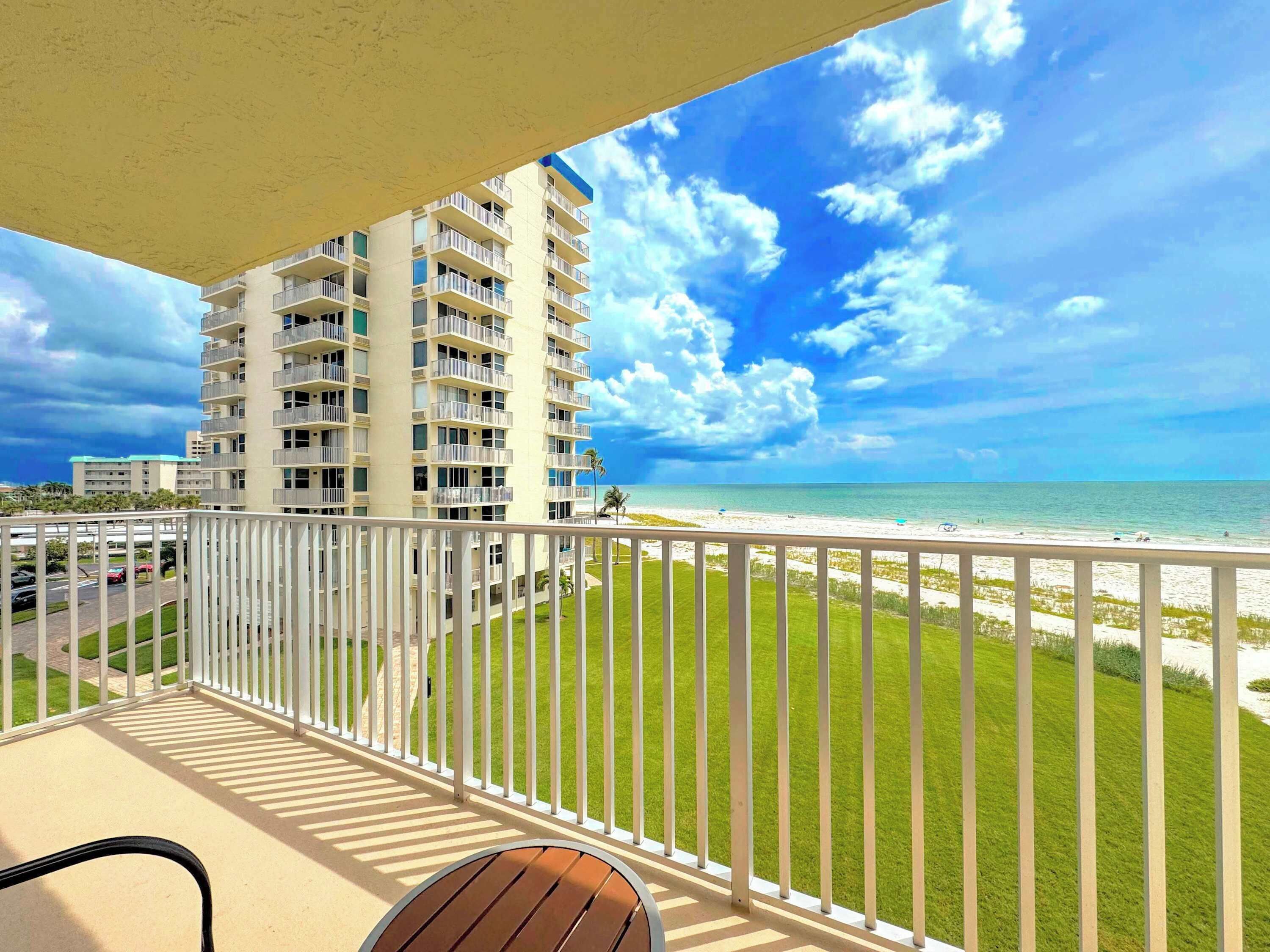 Un balcon avec vue sur une plage et un immeuble de grande hauteur.