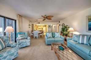 Ein Wohnzimmer mit blauem Sofa, Couchtisch und Deckenventilator.