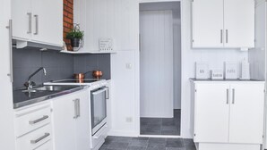Una cocina moderna con armarios blancos, un lavamanos de acero inoxidable y utensilios de cocina de cobre.
