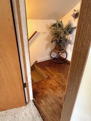 Een houten trap die uitkomt op een plateau met een bloempot op een tafeltje.