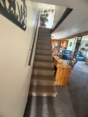 Una escalera que sube a un segundo piso, con un banco de madera al pie.