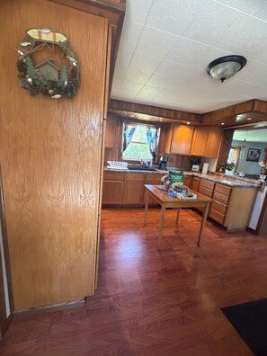 Una cocina con armarios de madera, una mesa de comedor y un ventanal con cortinas.