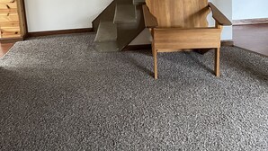 Una escalera de diseño moderno, una silla de madera y un adhesivo mural con la silueta de un ciervo y la palabra 'WELCOME'.