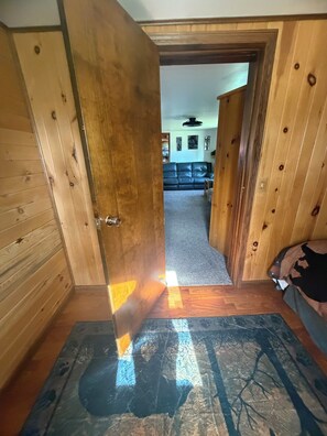 Un pasillo interior de madera que conduce a una sala de estar con un sofá y un perro.