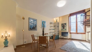 Un comedor con una mesa redonda, sillas, un florero y decoración en la pared.