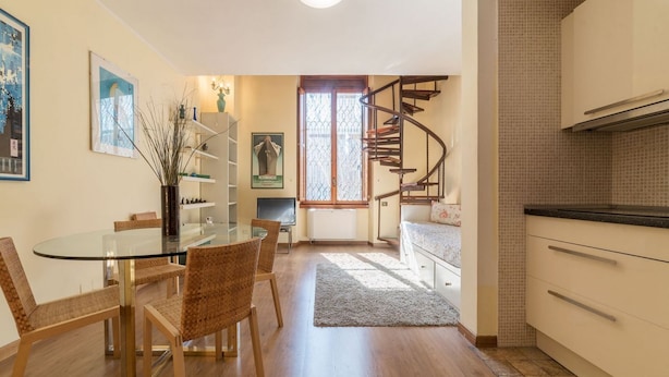 Un espacio habitable compacto con comedor, cocina y escalera en espiral.
