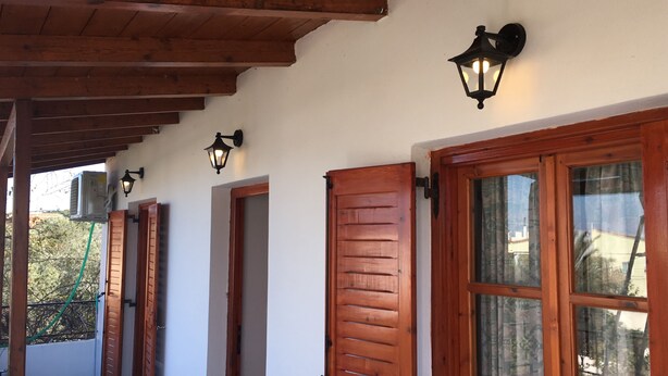 Un porche cubierto con contraventanas de madera y faroles fijados a la pared.