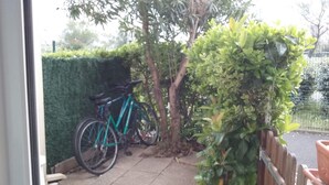En cykel parkeret ved siden af et træ og en hæk.