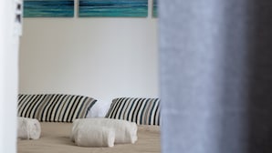 Et soveværelse med stribet sengetøj, en træsenggavl og havudsigt gennem et vindue.