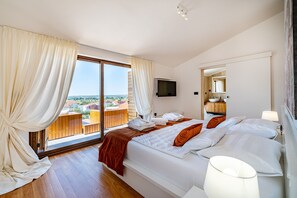A bedroom with a large bed, a TV, and a balcony with a view. - Villa Nena with heated pool, jacuzzi and sauna (Kakma)