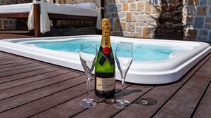 Una botella de Moet & Chandon y dos copas sobre una terraza de madera junto a un jacuzzi.
