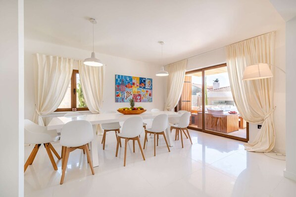 A modern dining area with a white table, chairs, and a fruit bowl. - Villa Nena with heated pool, jacuzzi and sauna (Kakma)