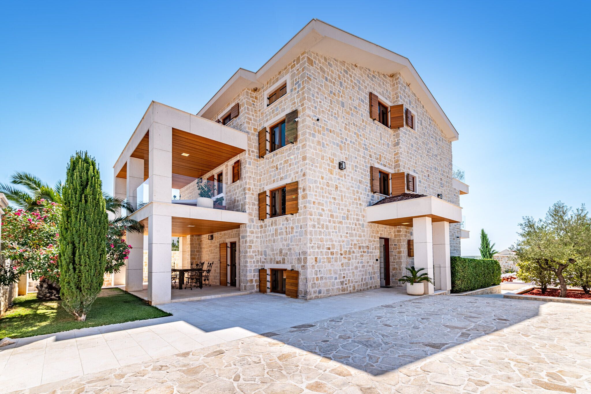 A multi-story stone building with balconies, a covered outdoor seating area, and a stone courtyard.