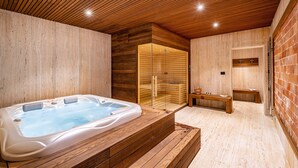 Un spa moderno con techo de madera, bañera de hidromasaje, sauna con paredes de vidrio y bancos de madera.